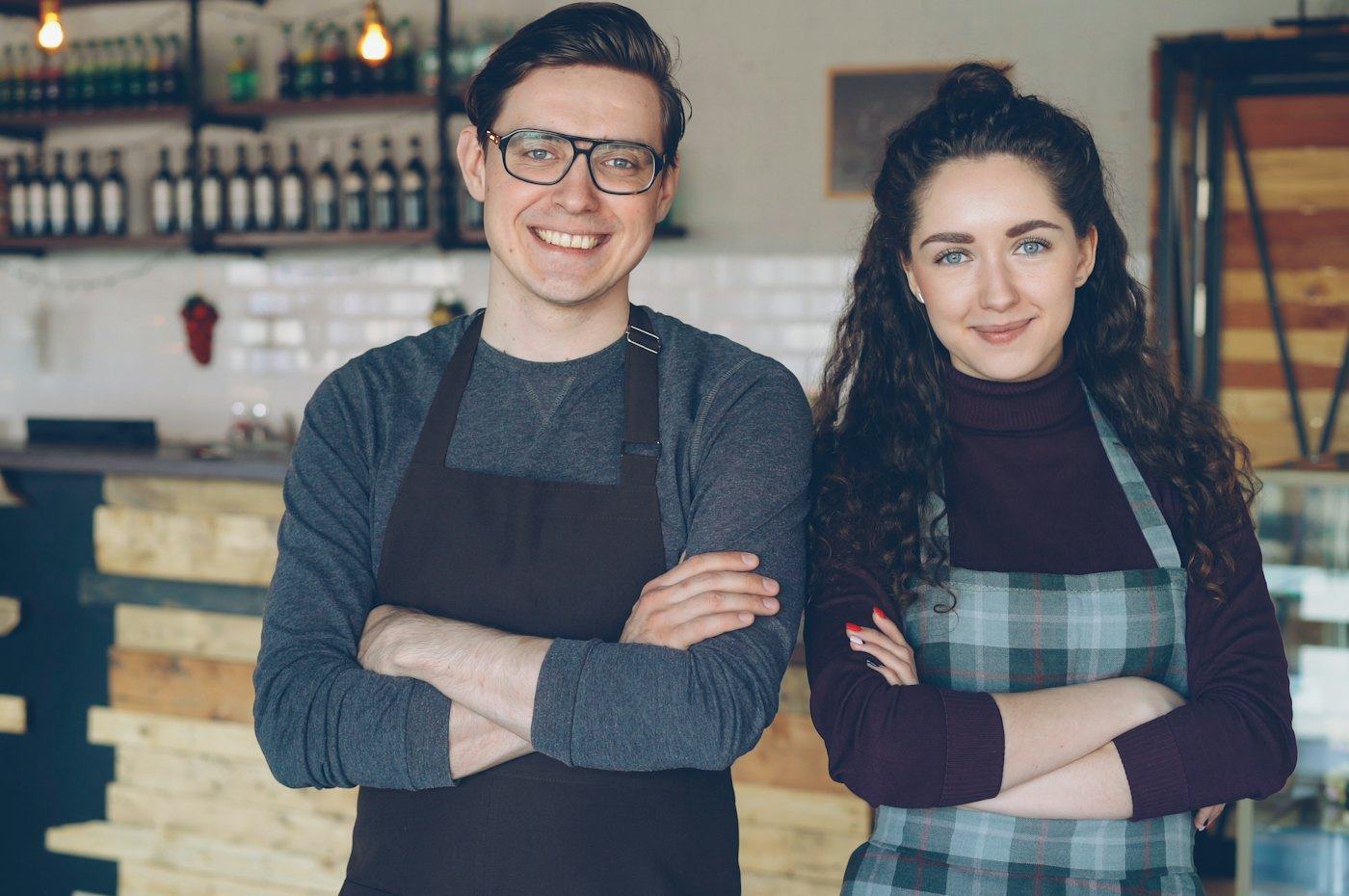 Two café owners standing proudly behind their counter