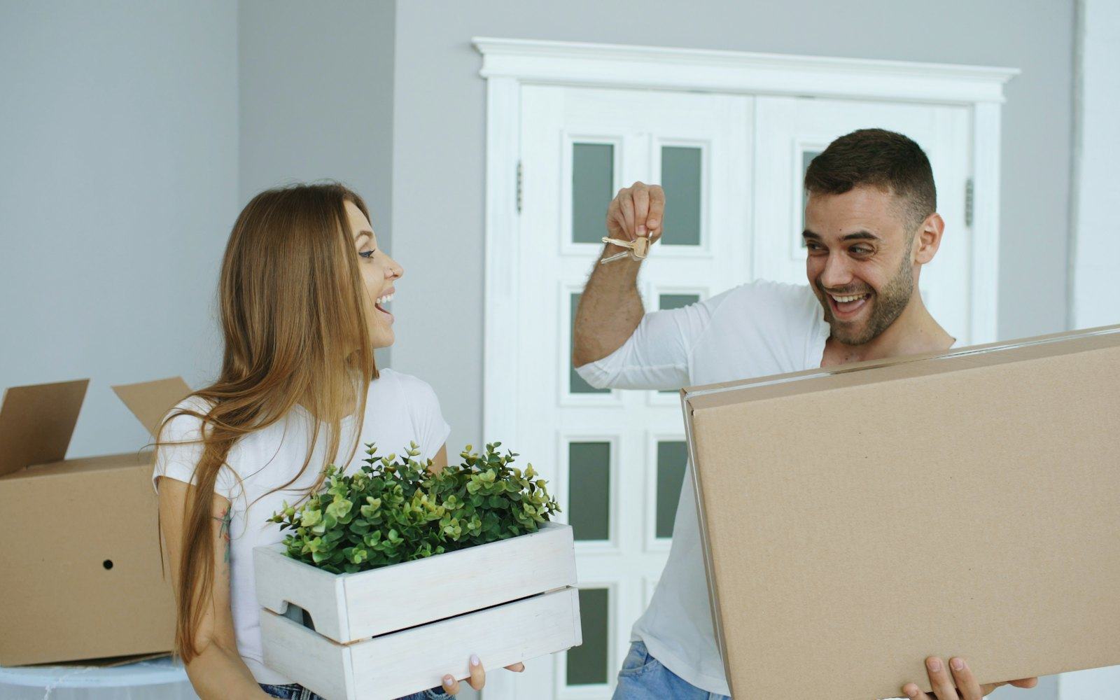 A couple carrying boxes into their new home